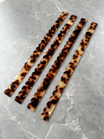 Set of four Mahj Mood tortoise acrylic scalloped mahjong pushers fanned diagonally on grey marble showing tortoiseshell pattern and scalloped design