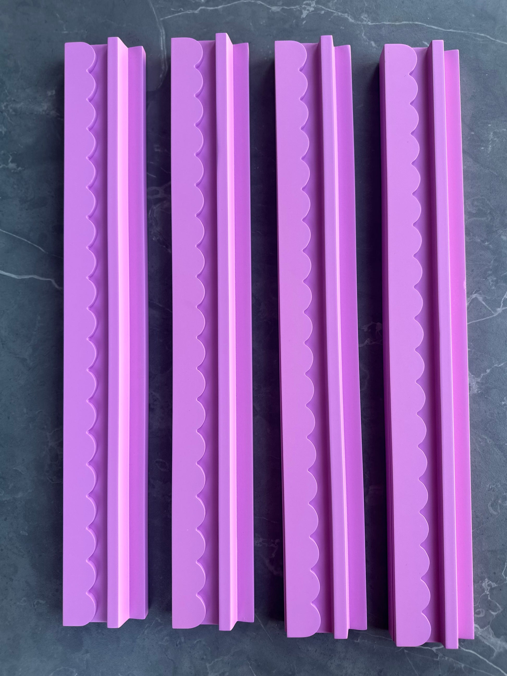 Mahj Mood scalloped pink wooden mahjong racks and pushers standing upright side by side on dark marble, full set of 4