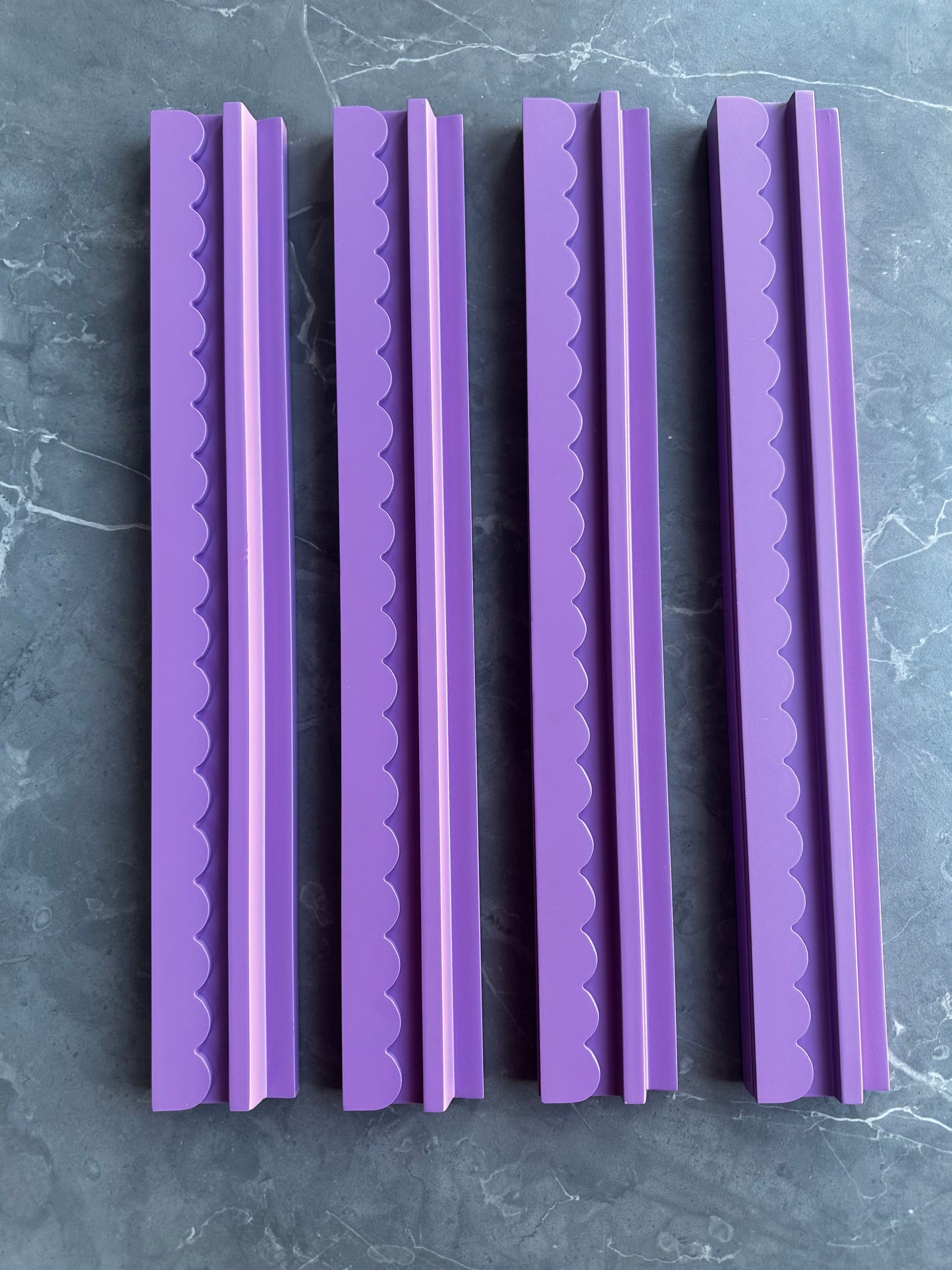 Mahj Mood scalloped purple wooden mahjong racks standing upright side by side on grey marble, showing all four racks in the set