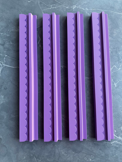 Mahj Mood scalloped purple wooden mahjong racks standing upright side by side on grey marble, showing all four racks in the set