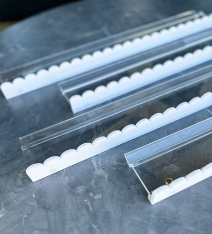 Mahj Mood scalloped white and clear acrylic mahjong racks stacked on grey marble showing solid white scalloped pusher edge and clear body