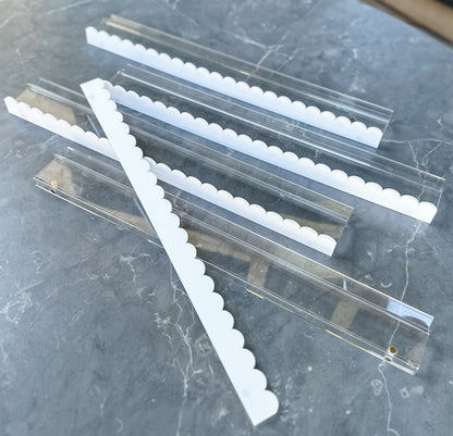 Mahj Mood scalloped white and clear acrylic mahjong racks fanned out on grey marble showing scalloped white pusher edges and clear acrylic body