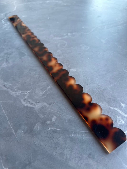 Single Mahj Mood tortoise acrylic scalloped mahjong pusher on grey marble surface showing tortoiseshell pattern and scalloped edge
