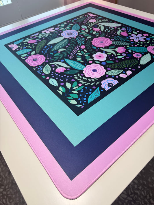 Mahj Mood Spring Fling Mat at an angle on a table showing layered navy, teal, and pink borders with dark floral center print